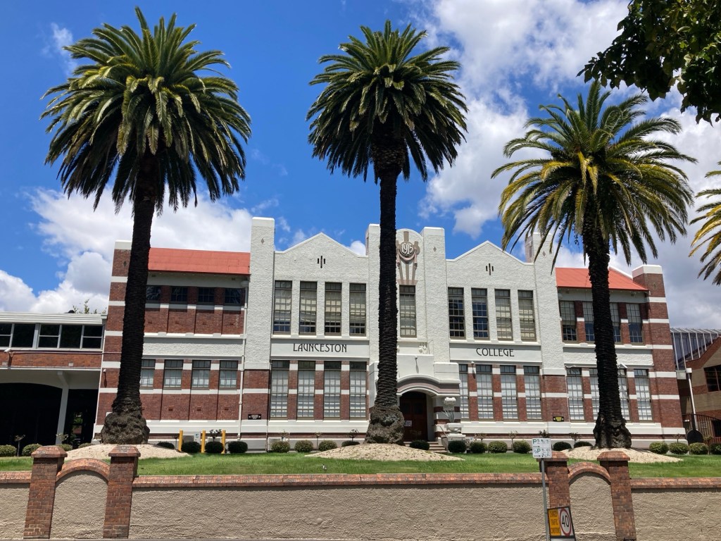 Photograph of Launceston College with three mature date palms in front of the building.