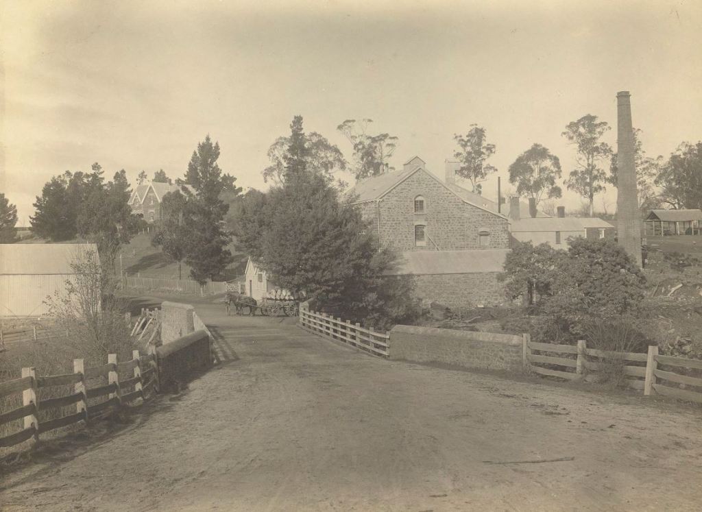 Old photograph looking across the bridge at Carrick towards Monds Mill. A horse and cart can be seen outside the mill.